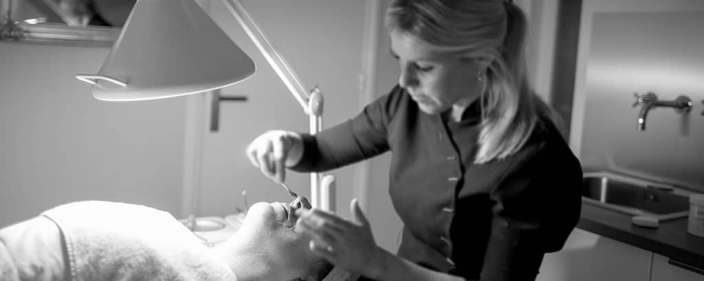 Jolanda geeft een gezichtsbehandeling in de behandelkamer van La Délice; de cliënt ligt onder een loeplamp.